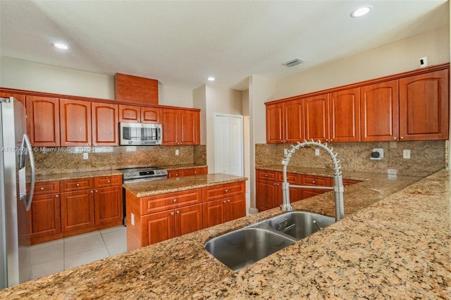 1411 SW 149th Pl, Miami, FL 33194 - kitchen with stainless steel appliances, light stone countertops, tasteful backsplash, recessed lighting, and brown cabinetry