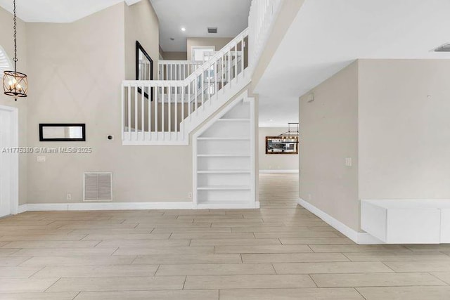 10766 Crescendo Cir, Boca Raton, FL 33498 - staircase with a chandelier, wood finished floors, baseboards, built in shelves, and a towering ceiling