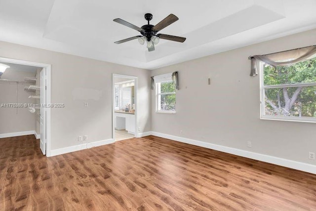 10766 Crescendo Cir, Boca Raton, FL 33498 - unfurnished bedroom featuring a walk in closet, baseboards, wood finished floors, and a raised ceiling