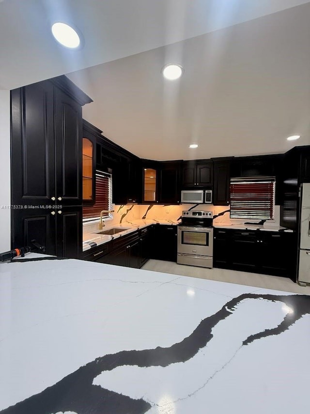 4529 SW 24th St, Fort Lauderdale, FL 33317 - kitchen featuring glass insert cabinets, a sink, dark cabinetry, stainless steel appliances, and light stone counters