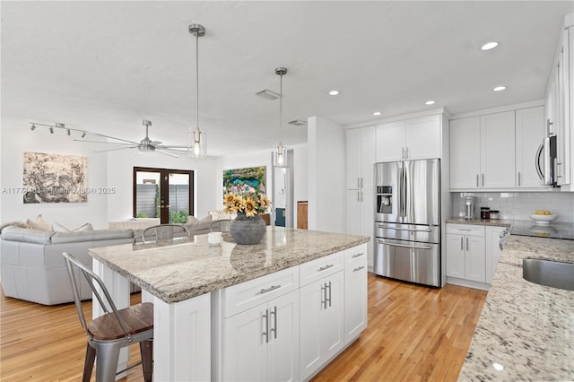kitchen featuring a kitchen breakfast bar, light wood-type flooring, a center island, stainless steel appliances, and open floor plan