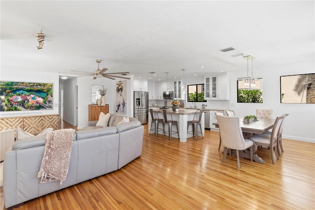 living area featuring light wood-style flooring, visible vents, and ceiling fan