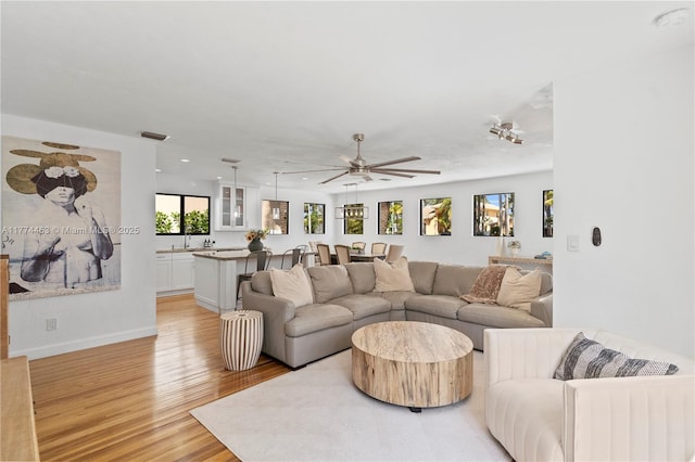 living area featuring visible vents, baseboards, ceiling fan, light wood-type flooring, and recessed lighting