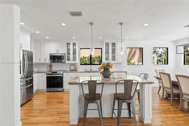 kitchen with a breakfast bar, light wood-style flooring, backsplash, visible vents, and stainless steel appliances
