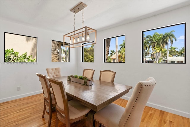 dining area with light wood-style flooring, baseboards, plenty of natural light, and a notable chandelier