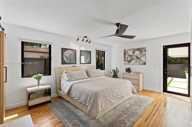 bedroom with access to outside, light wood-style floors, baseboards, and multiple windows