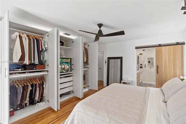 bedroom with visible vents, a closet, a ceiling fan, light wood finished floors, and ensuite bath