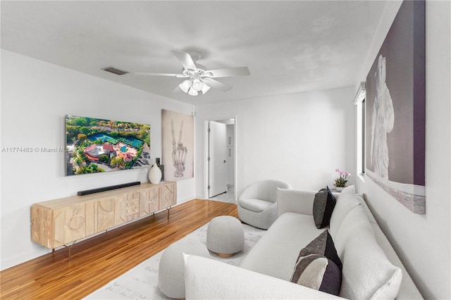 living room with ceiling fan, visible vents, and wood finished floors