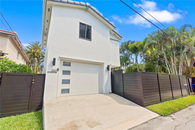 exterior space with driveway, fence, a garage, and stucco siding