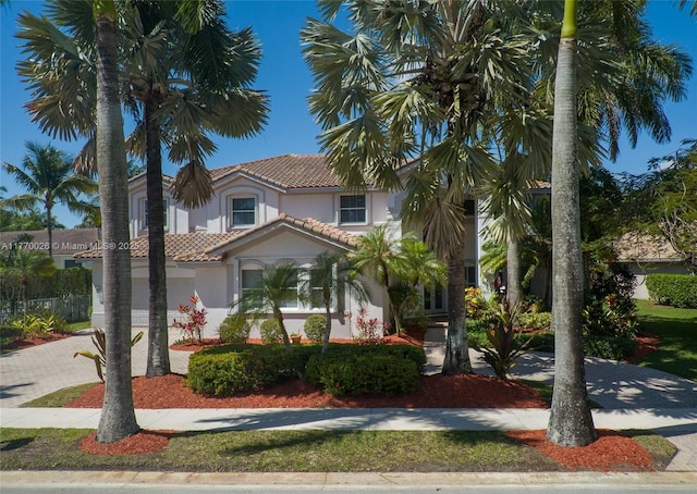 mediterranean / spanish-style home with a tiled roof, decorative driveway, and stucco siding