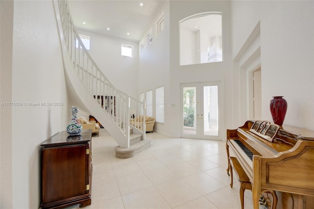 foyer entrance with light tile patterned floors, a towering ceiling, recessed lighting, stairway, and french doors