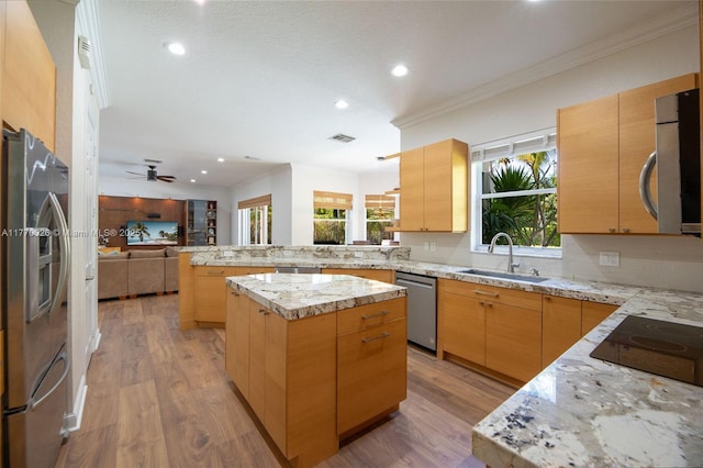 kitchen featuring crown molding, a peninsula, light wood-type flooring, appliances with stainless steel finishes, and a sink