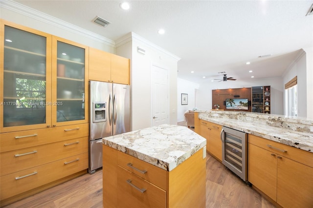 kitchen with light wood-type flooring, ornamental molding, stainless steel refrigerator with ice dispenser, visible vents, and beverage cooler