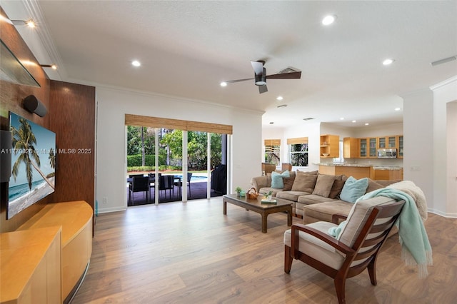 living area with recessed lighting, visible vents, ornamental molding, and ceiling fan