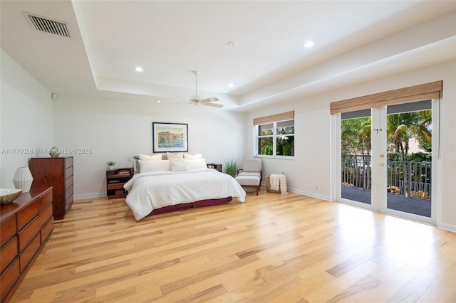 bedroom featuring visible vents, light wood-type flooring, a tray ceiling, recessed lighting, and access to outside
