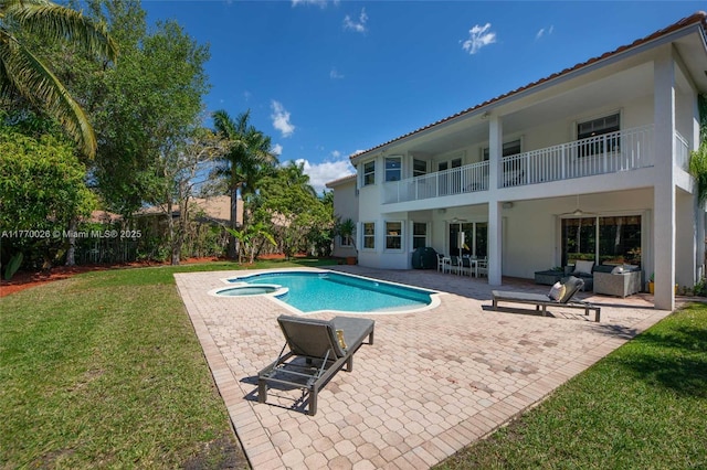 view of pool featuring a patio, a pool with connected hot tub, fence, and a lawn