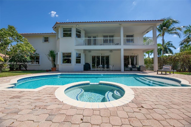 rear view of property featuring a patio area, ceiling fan, a tile roof, stucco siding, and a balcony