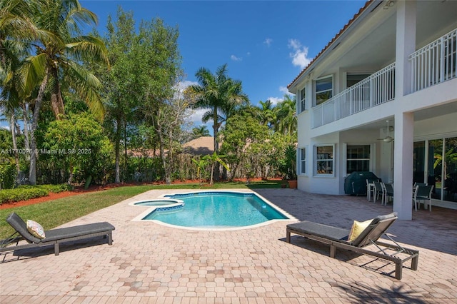view of swimming pool featuring a pool with connected hot tub, grilling area, a ceiling fan, and a patio