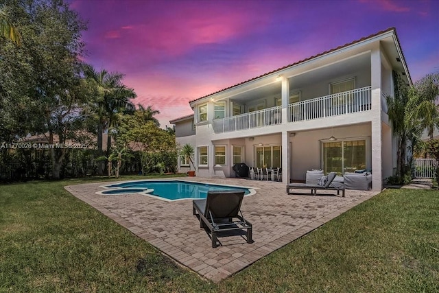 1427 Victoria Isle Dr, Weston, FL 33327 - back of property at dusk with a balcony, stucco siding, a patio, and a pool with connected hot tub