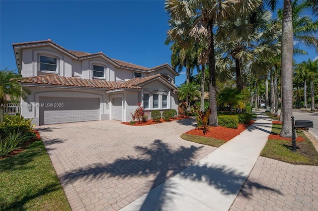 1427 Victoria Isle Dr, Weston, FL 33327 - mediterranean / spanish home featuring stucco siding, a tiled roof, decorative driveway, and an attached garage