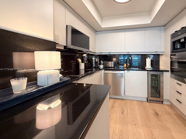 1331 Brickell Bay Dr Unit 506, Miami, FL 33131 - kitchen with wine cooler, stainless steel appliances, a sink, dark countertops, and a tray ceiling