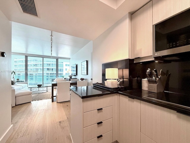 1331 Brickell Bay Dr Unit 506, Miami, FL 33131 - kitchen with stainless steel microwave, a wall of windows, open floor plan, a peninsula, and light wood-style flooring
