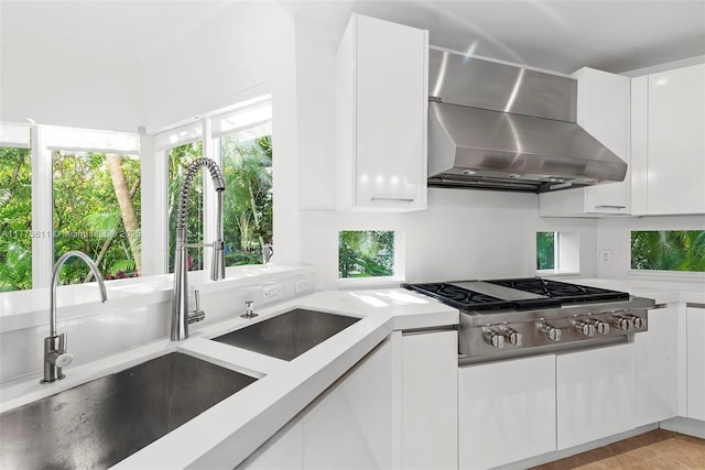 455 Centre Is, Golden Beach, FL 33160 - kitchen with a sink, white cabinets, stainless steel gas cooktop, and wall chimney exhaust hood