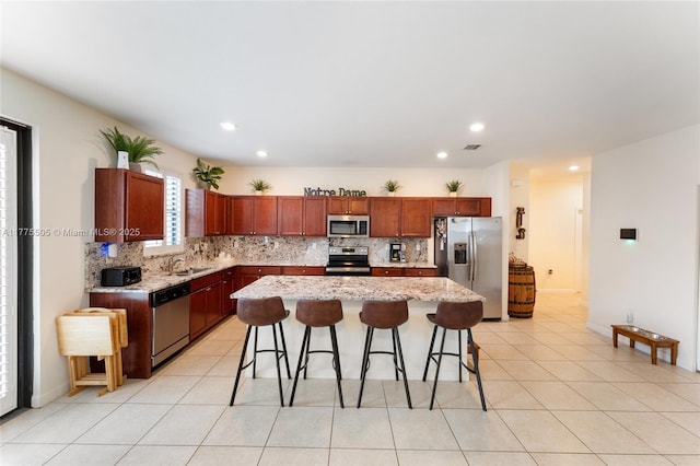 kitchen featuring a breakfast bar, a sink, backsplash, and appliances with stainless steel finishes