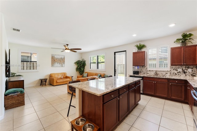 kitchen featuring a center island, light tile patterned flooring, a sink, visible vents, and a ceiling fan