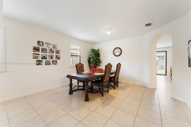 dining area with arched walkways, visible vents, a healthy amount of sunlight, and light tile patterned floors