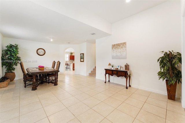 dining area featuring light tile patterned flooring, visible vents, baseboards, stairway, and arched walkways