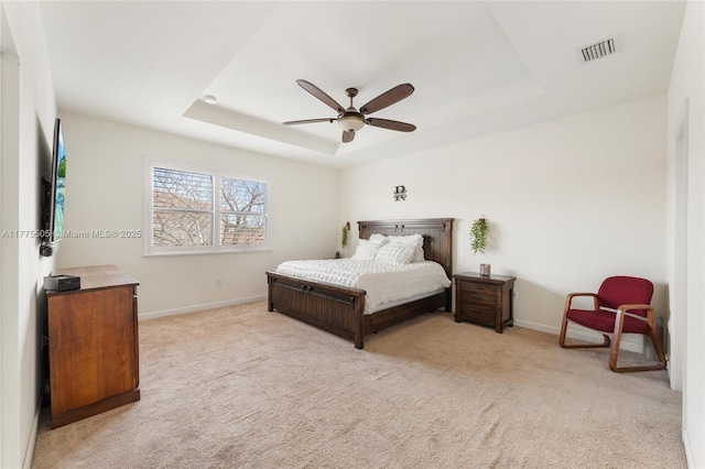 bedroom with a tray ceiling, carpet floors, a ceiling fan, baseboards, and visible vents