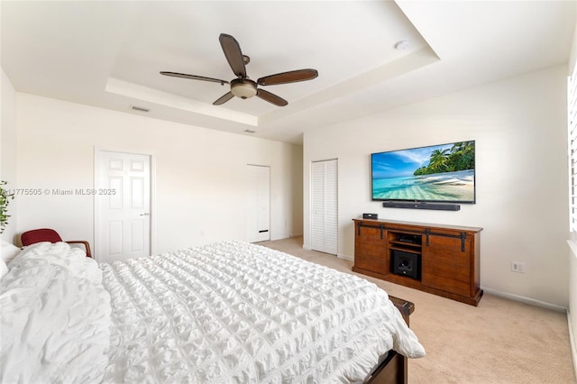 bedroom featuring light carpet, baseboards, visible vents, and a raised ceiling