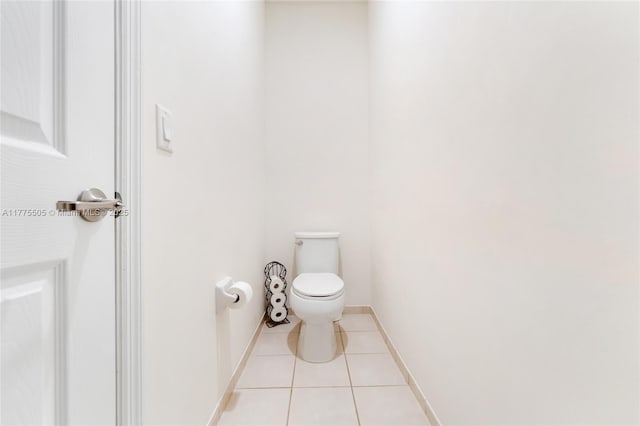 bathroom with baseboards, toilet, and tile patterned flooring