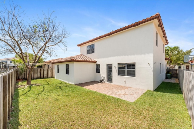 rear view of house with a tiled roof, a patio, a fenced backyard, stucco siding, and a yard