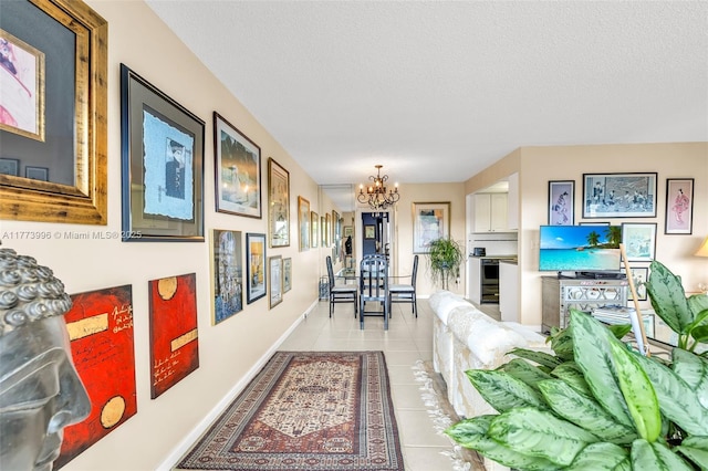 hall with baseboards, a notable chandelier, a textured ceiling, and light tile patterned floors