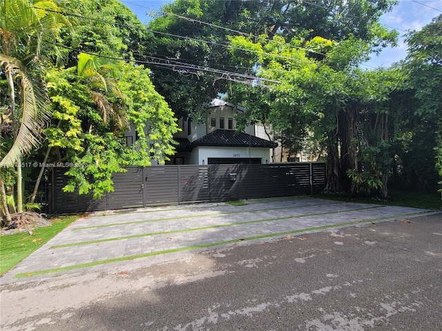 view of car parking featuring driveway, a gate, and fence