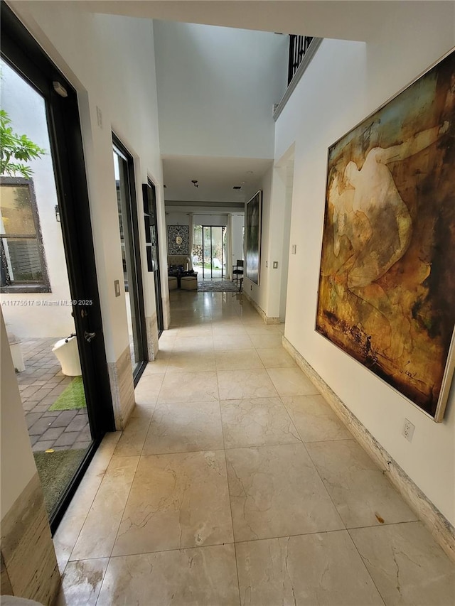 corridor with baseboards and a towering ceiling