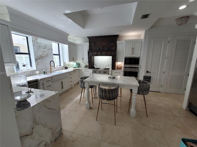 kitchen with decorative backsplash, stainless steel oven, a sink, light stone counters, and built in microwave