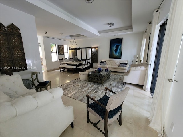 living area with a tray ceiling and light tile patterned flooring
