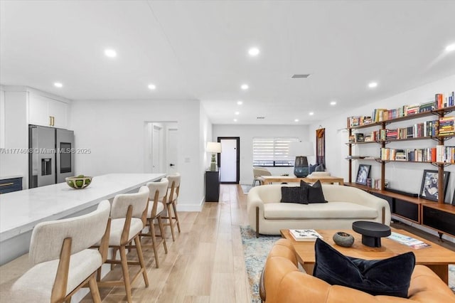 living area with baseboards, recessed lighting, visible vents, and light wood-type flooring