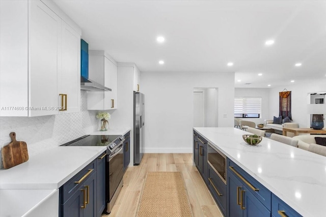 kitchen with wall chimney exhaust hood, white cabinets, blue cabinets, and appliances with stainless steel finishes