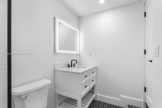 bathroom featuring baseboards, toilet, vanity, and recessed lighting