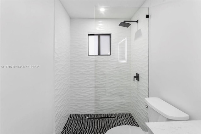 full bathroom with a tile shower, toilet, and vanity