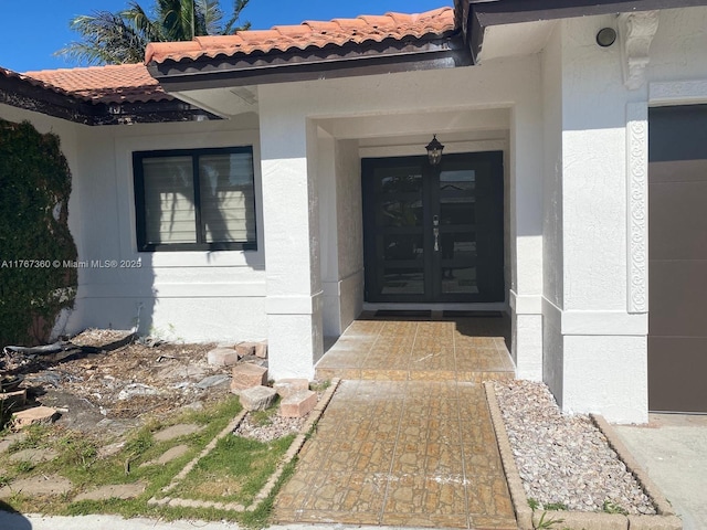 view of exterior entry with stucco siding and a tile roof