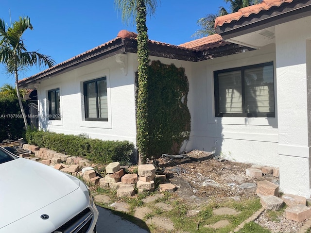 view of side of home with a tiled roof and stucco siding