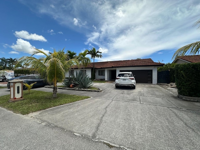 ranch-style house with an attached garage, concrete driveway, stucco siding, and a tile roof