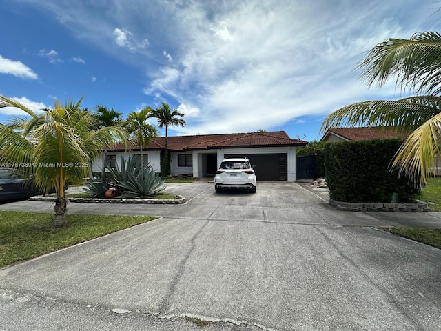 single story home featuring a tile roof, a garage, and concrete driveway