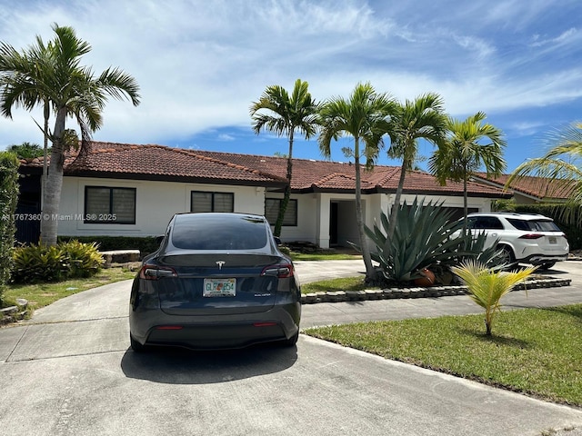 single story home featuring concrete driveway, stucco siding, and a tile roof