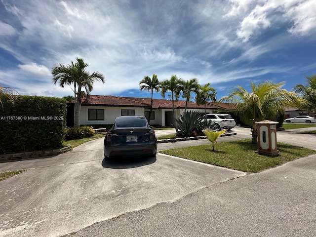 ranch-style home with concrete driveway, stucco siding, and a tiled roof